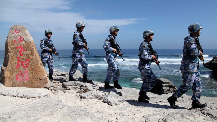 Soldiers of China's People's Liberation Army Navy form a line as they patrol on an island in the South China Sea.
