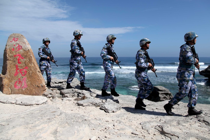 Soldiers of China's People's Liberation Army Navy form a line as they patrol on an island in the South China Sea.