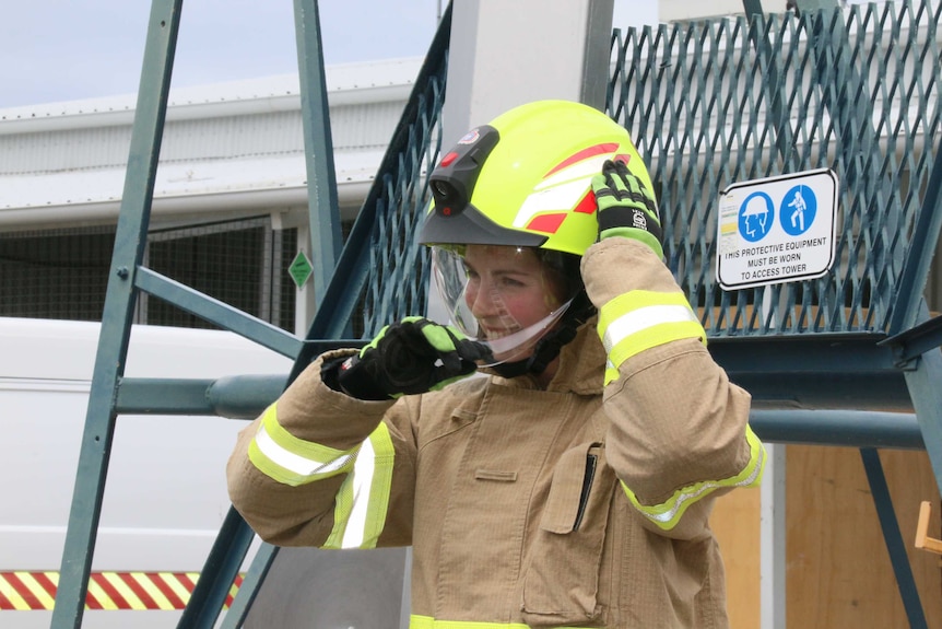 A young female firefighter adjusts her helmet.