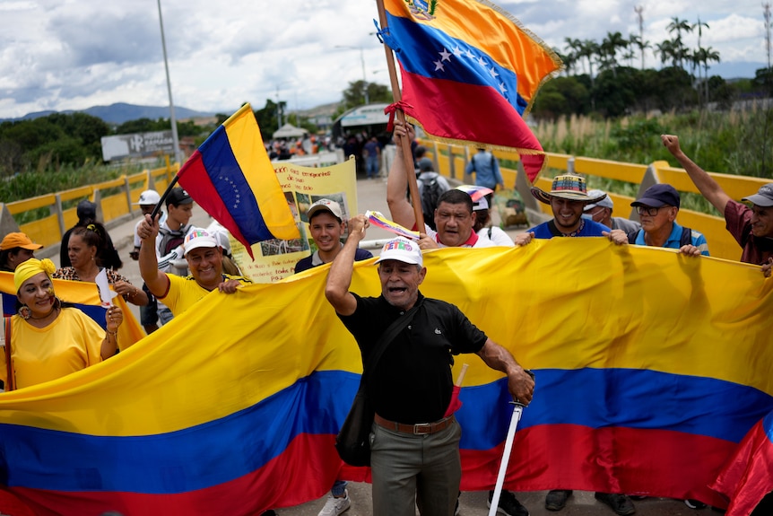 A group of people carrying a large Colombia flag cheering