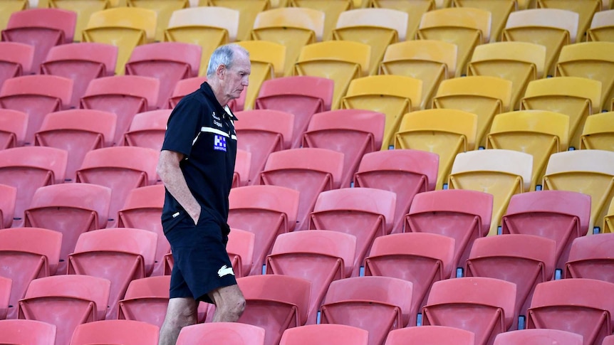 South Sydney Rabbitohs coach Wayne Bennett walks through the red and yellow seats at Suncorp Stadium.