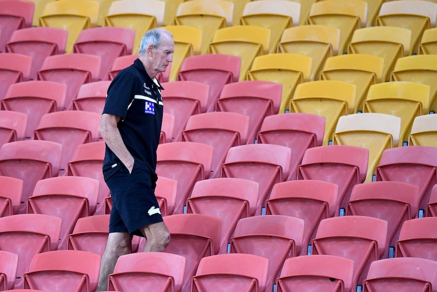 South Sydney Rabbitohs coach Wayne Bennett walks through the red and yellow seats at Suncorp Stadium.