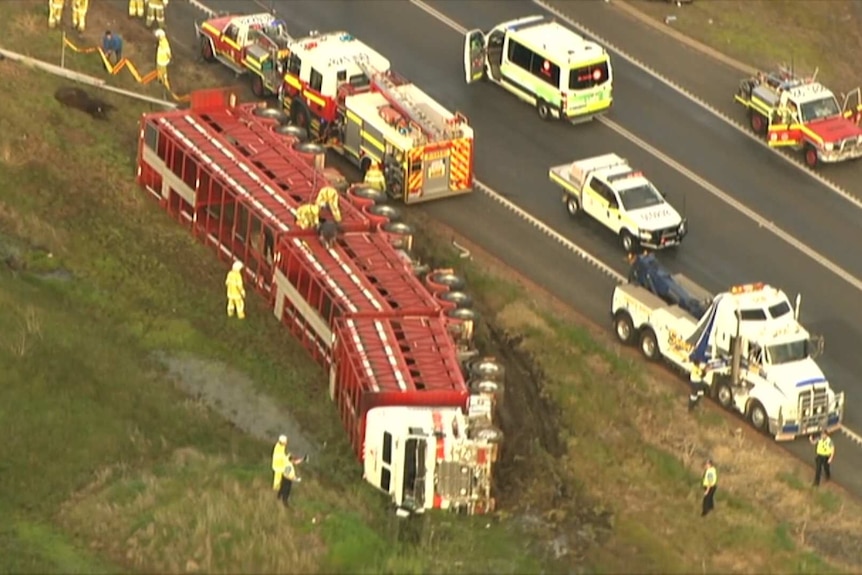 An aerial shot of a cattle truck lying on its side along a section of a highway