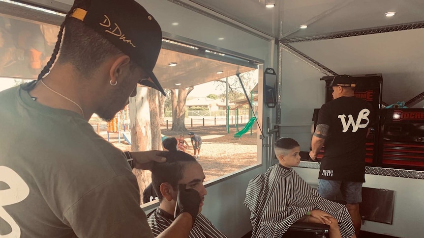 A barber cuts a boy's hair in a mobile barber shop.
