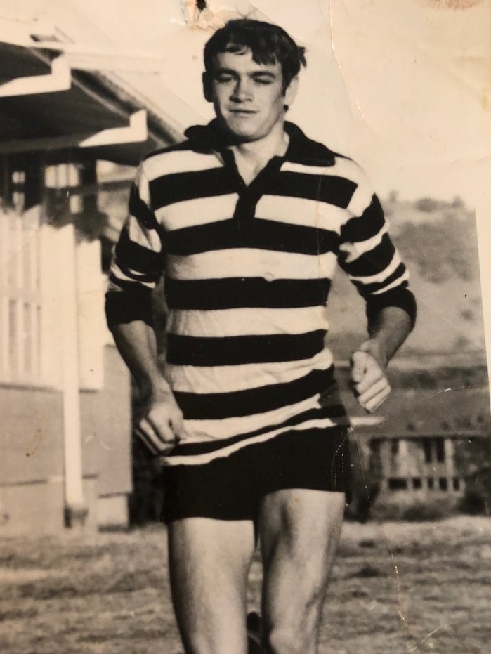 Black and white photo of Cassidy in striped footy jumper running.