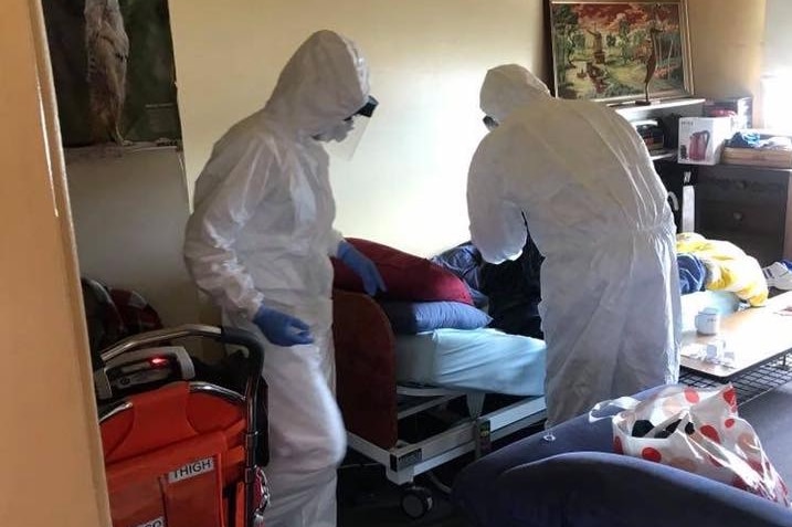 Two people in white Hazmat suits in a home.