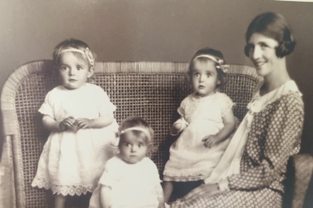An old sepia-tone photograph of young triplets and their mother.