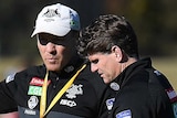Two Collingwood assistant coaches talk at a Magpies training session.