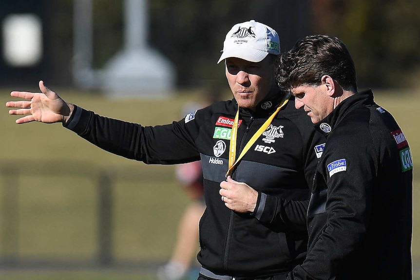 Two Collingwood assistant coaches talk at a Magpies training session.