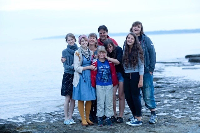 A family of eight pose for a group photo on a beach in Sweden