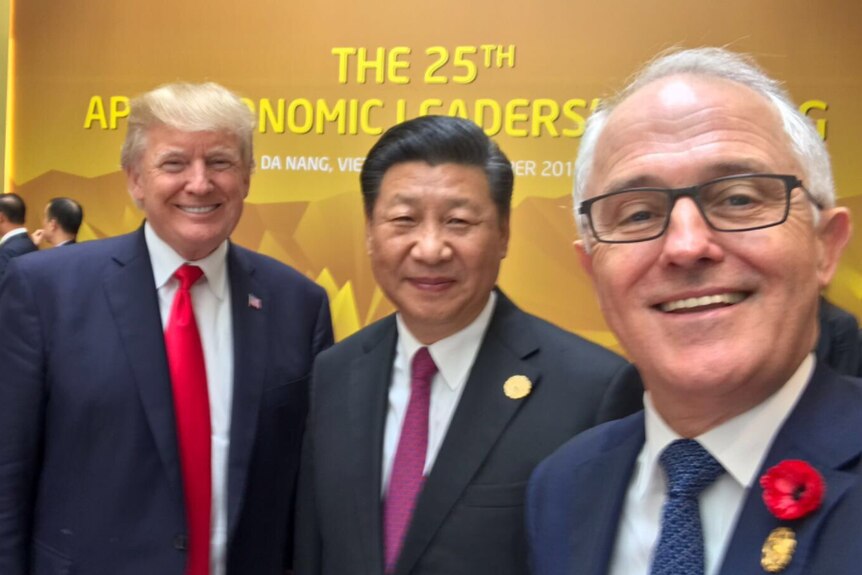 Three politicians smile in a selfie at APEC