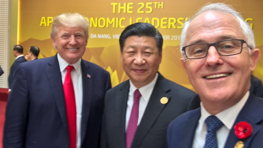 Three politicians smile in a selfie at APEC