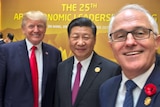 Three politicians smile in a selfie at APEC