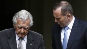 Bob Hawke holds a walking cane in a doorway as he stands next to Tony Abbott who offers a hand