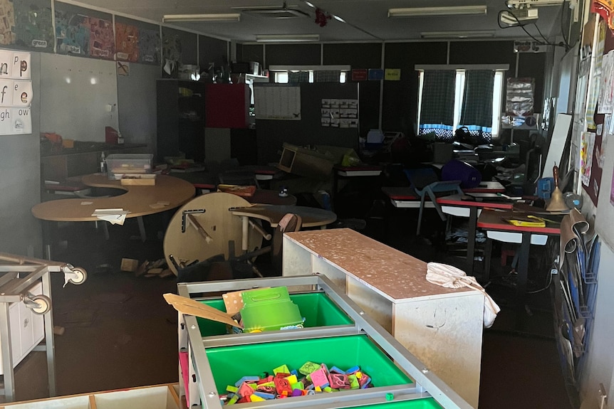 A Pigeon Hole school classroom is seen flooded with some upturned and damaged furniture.