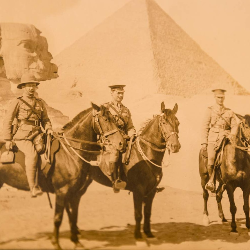Walter Cass is shown on a horse flanked by two other men on horses in front of a pyramid and a sphinx in Egypt.