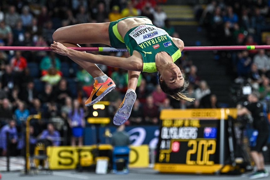 An Australian female athlete arches her back to complete a successful clearance of the bar in a high jump competition.  