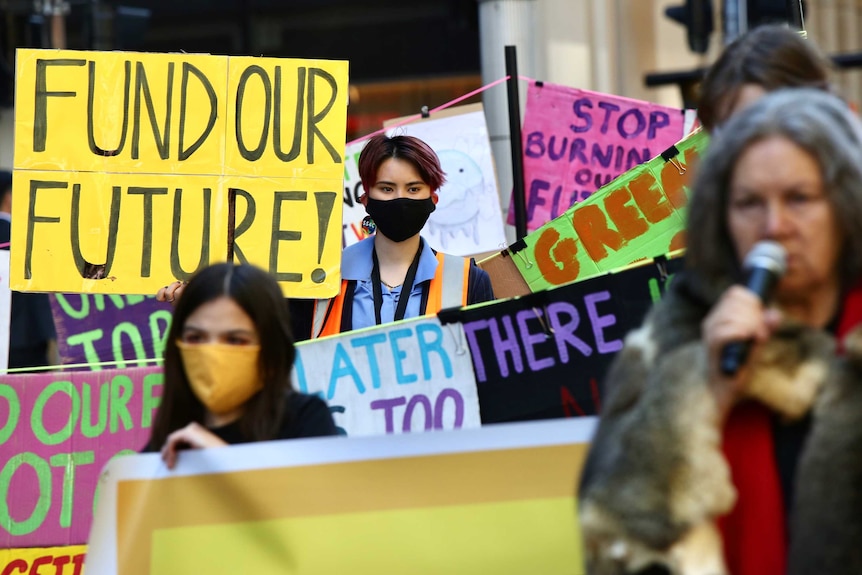 A group of people holding placards with climate slogans.