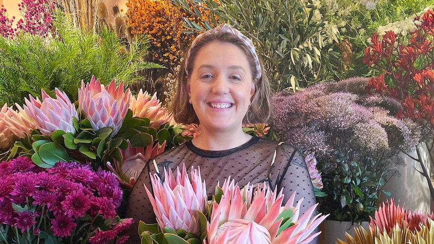 Florist Justine Ellborn surrounded by flowers in a story about why it's hard to buy flowers during coronavirus pandemic.