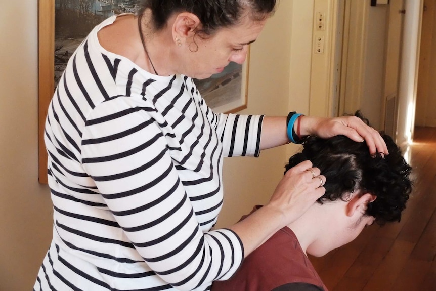 Anna Cukierman from Melbourne checks for lice from a boy's head.