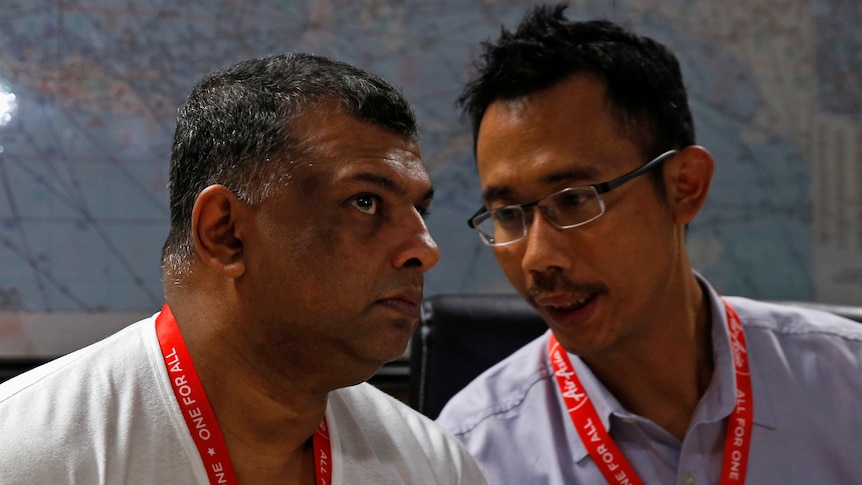 AirAsia CEO Tony Fernandes talks with director Sunu Widyatmoko at a news conference in Surabaya