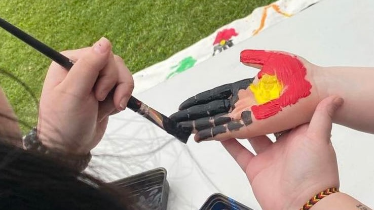 Woman painting young girl's hand with Aboriginal flag