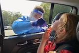 A child in a car receives a COVID nasal swab