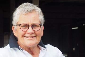 A close up photo of a woman with glasses in a white shirt