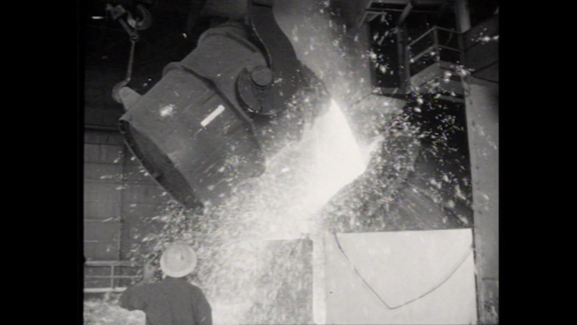 Black and white archival image of the Whyalla Steelworks in operation, showing molten steel being poured out.