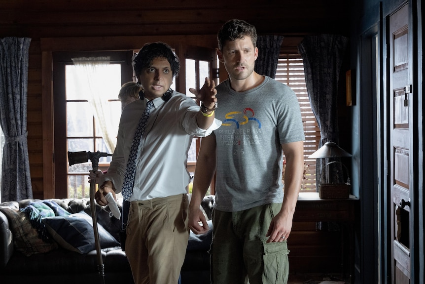 Ben Aldridge and M. Night Shyamalan standing beside each other, one with an arm outstretched pointing, the other looking stunned