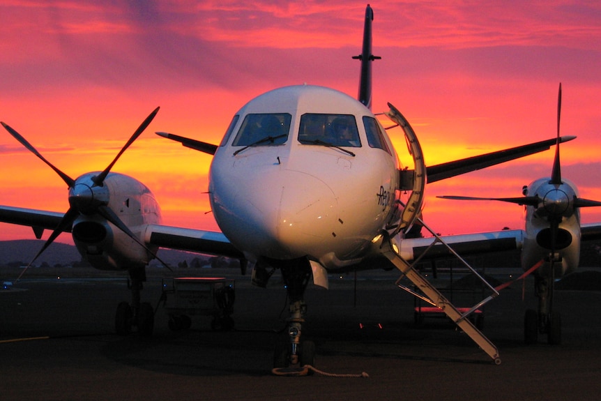 A close up of the front of a small plane with a sunset behind