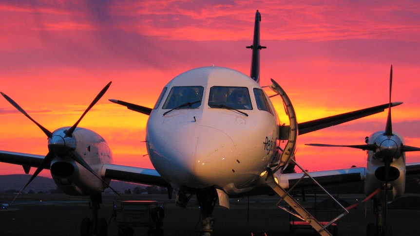 A close up of the front of a small plane with a sunset behind