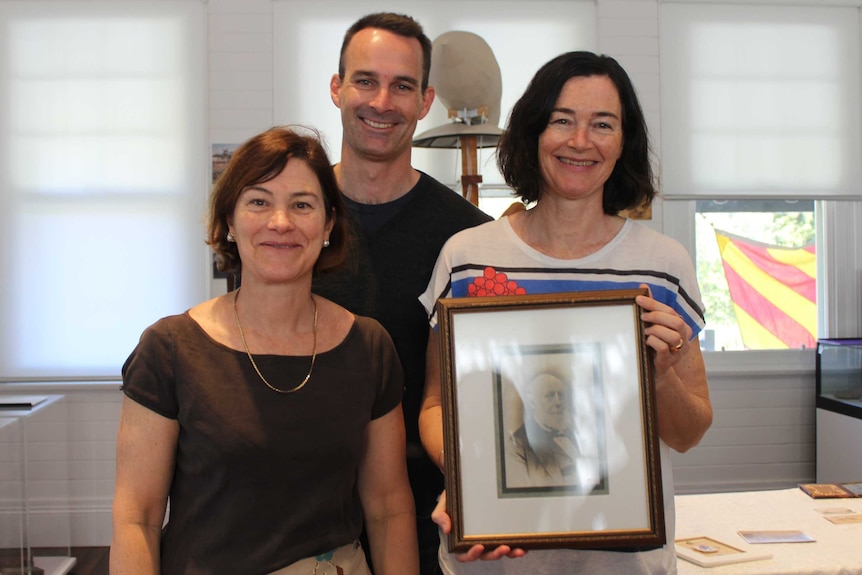 Patti Mckenzie's three children hold a photograph of their famous ancestor in the Coffs Harbour Regional Museum.
