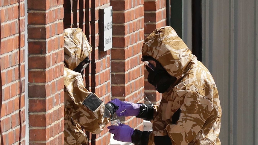 Emergency workers in military protective suits search the fenced off House