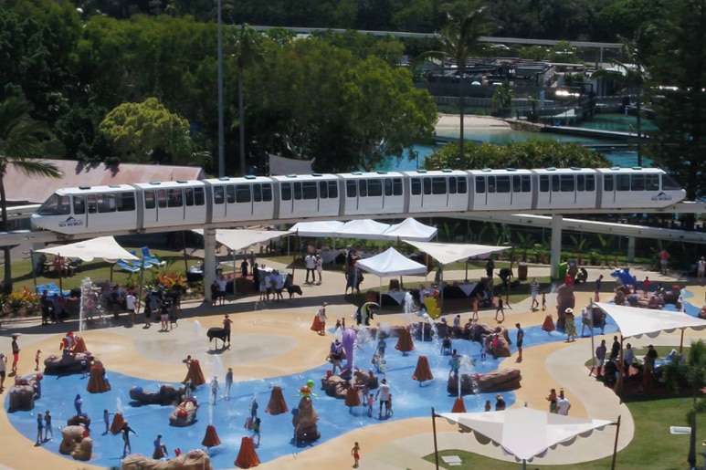 Monorail running above a theme park's water attraction.