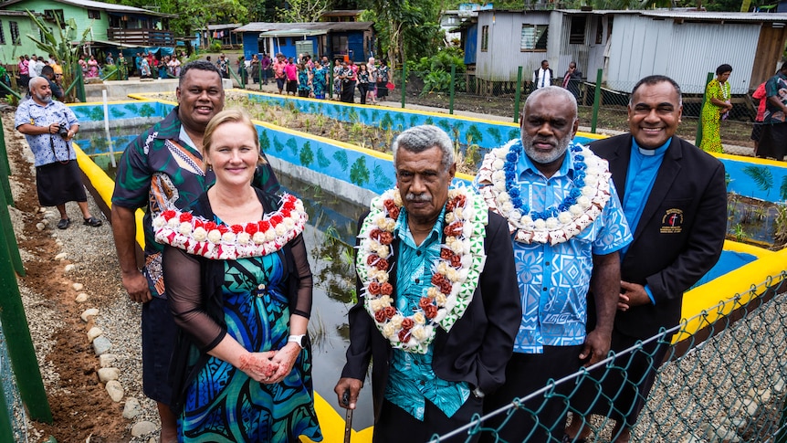 Four men and one woman stand in front of constructed wetland.