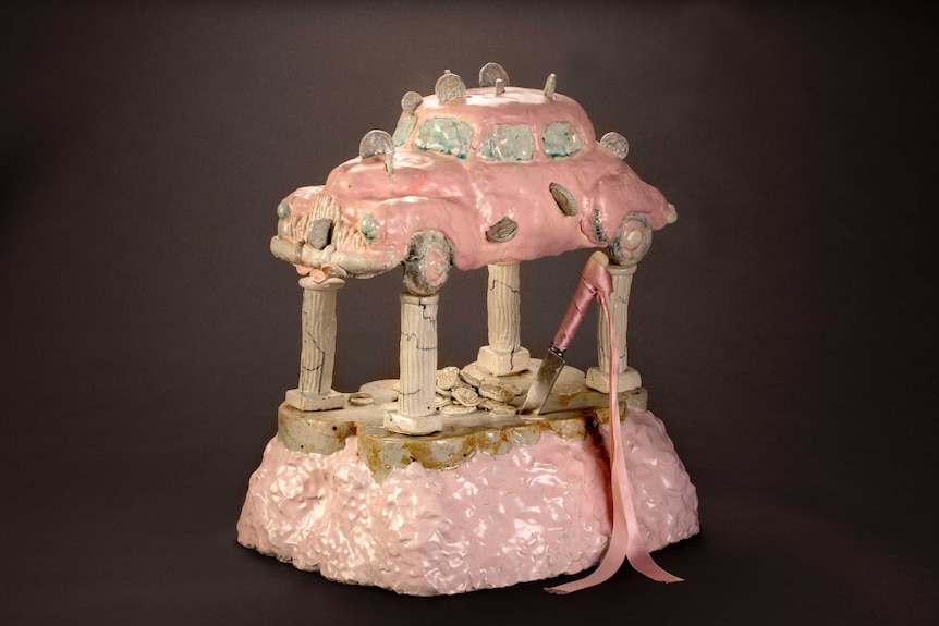A sculpture of a pink early-model Holden car sitting atop a wedding cake