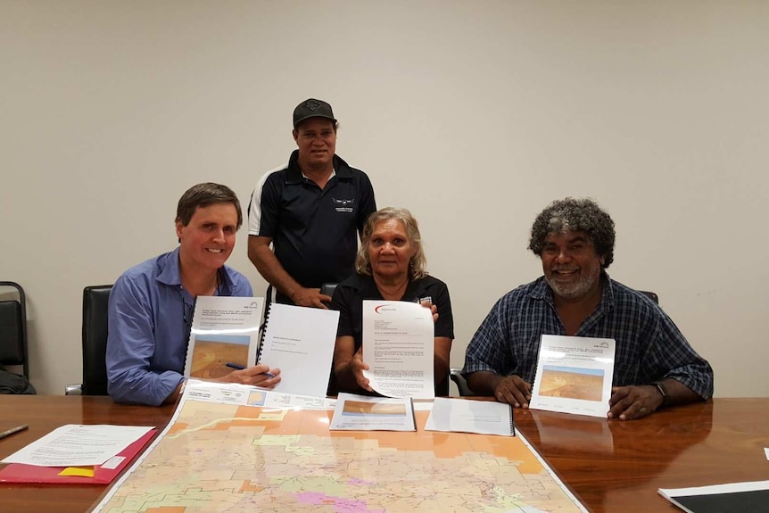 Four traditional owners sit with mining executive signing a mining agreement