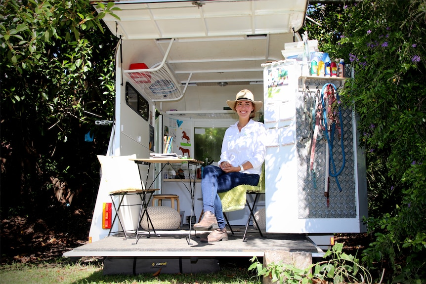 Sam Tassini (woman) sits in the horse float that she has converted into her office.