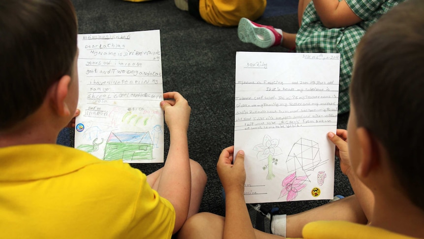 Two students hold letters they have written to pen pals about their hobbies, family and school life.