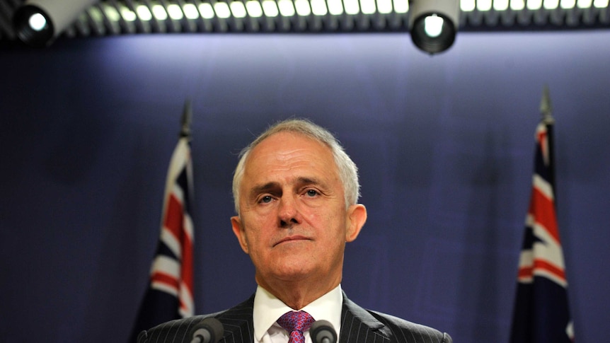 Prime Minister Malcolm Turnbull stands in front of Australian flags addressing the media.