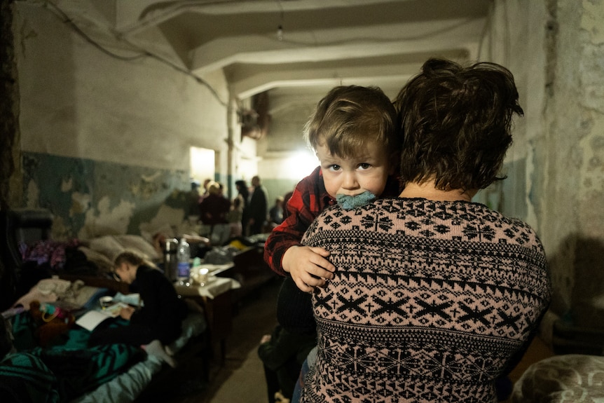 A woman holds a child in an improvised bomb shelter.