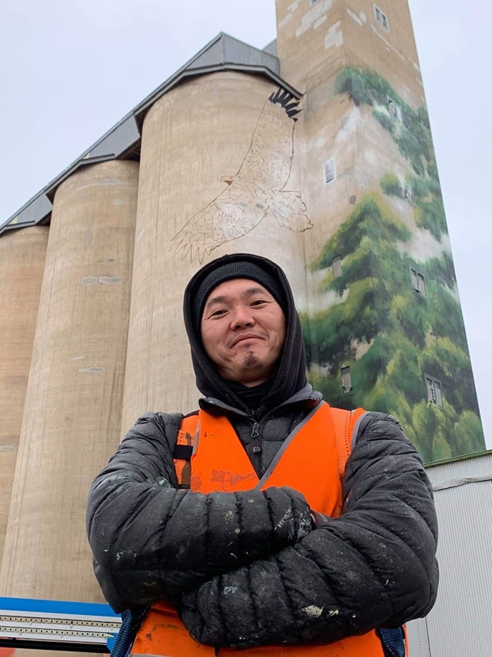 Man stands in front of silos