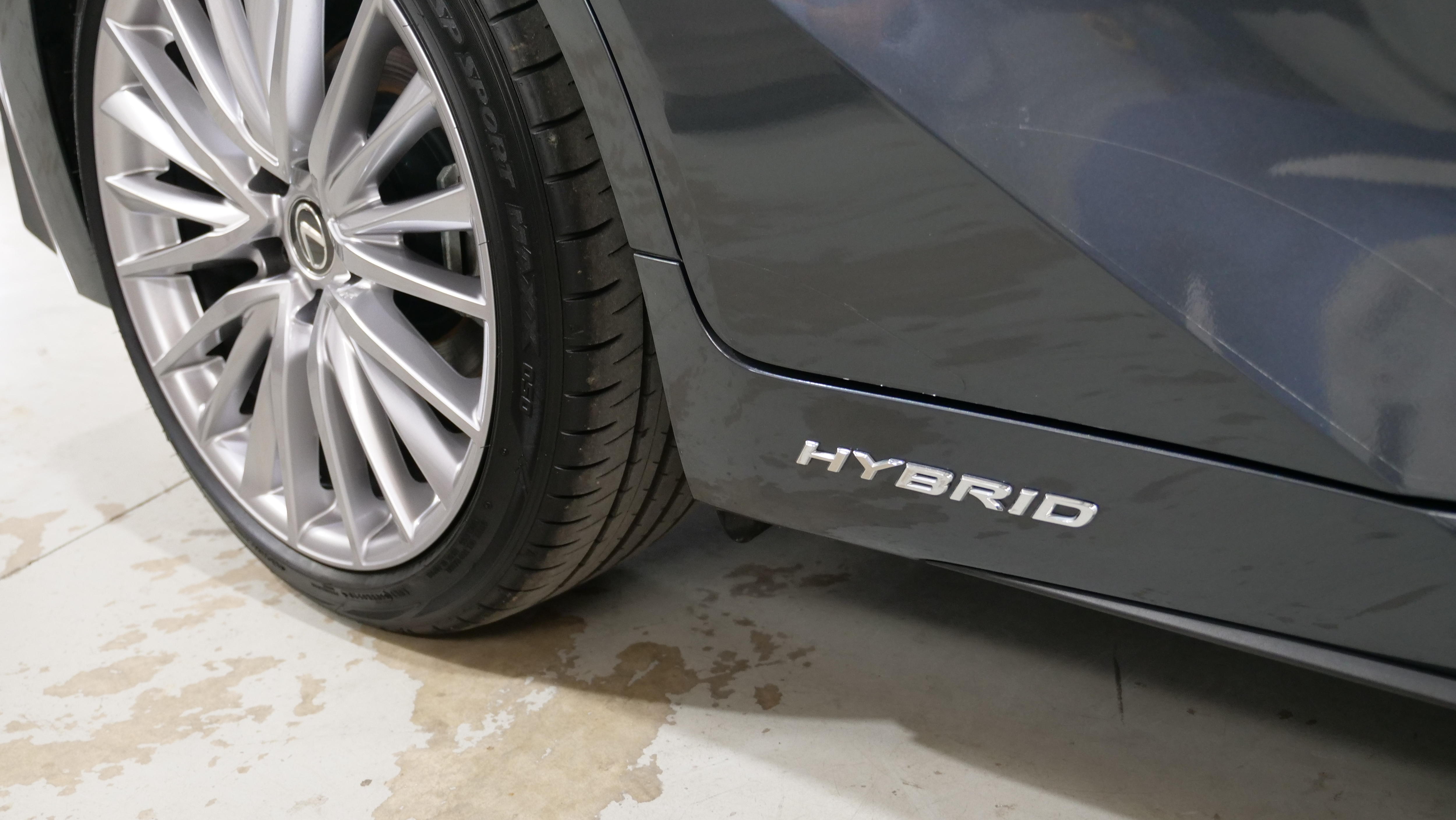 A close shot of the side of a car, featuring the word hybrid written in silver