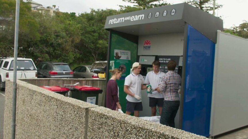 Students stand at bottle recycling station in carpark