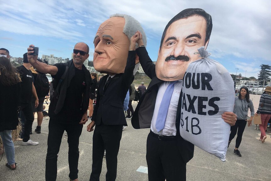 A man takes a selfie with a fake Malcolm Turnbull and Guatam Adani.