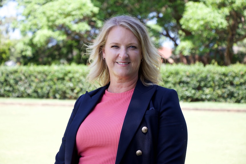 A woman with blond hair in pink shirt and blazer 