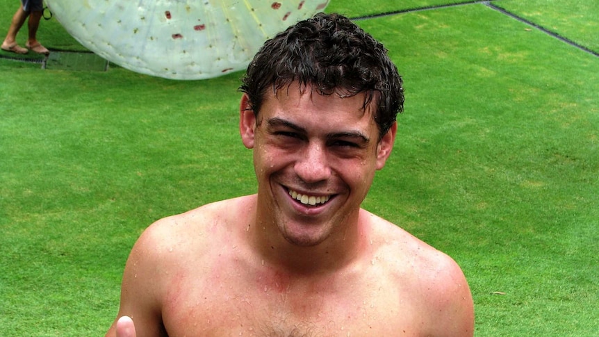 A young man with a big smile on his face in a green grass field