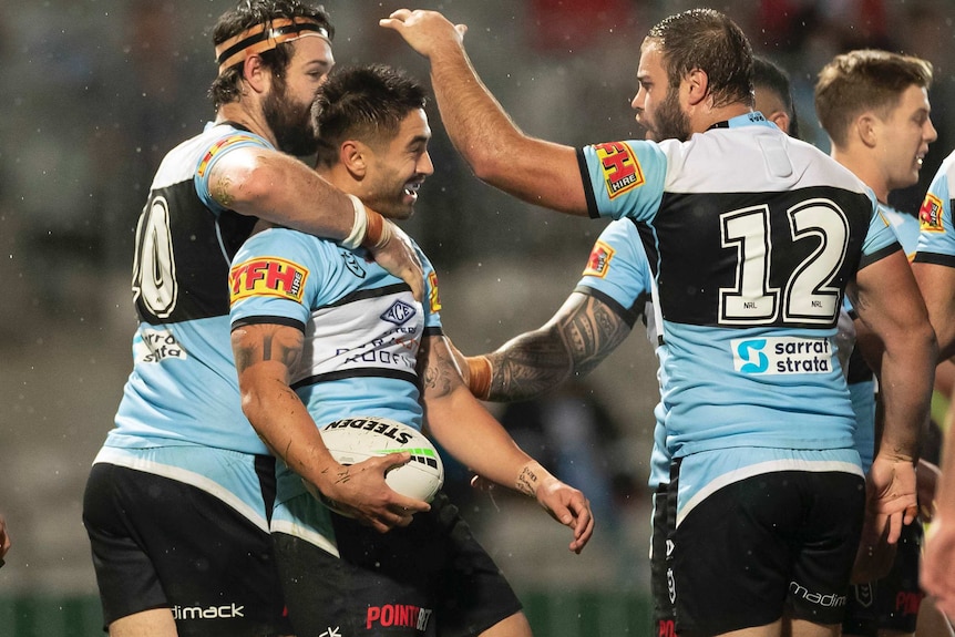 A smiling Shaun Johnson is hugged and patted on the head