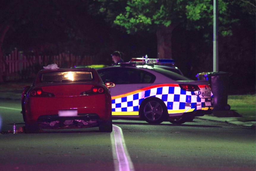 Night shot of a red car next to a police car where pedestrians were mown down in Canning Vale.